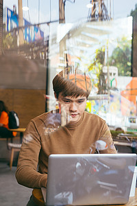 一位年轻人在学生咖啡馆计算时喝咖啡的画面 在网吧上背景图片