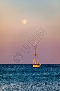 拥抱太阳的月亮满月从水面上升起 前景是一艘小帆船 日落时升起月亮的帆船 月亮升起在海面上 游艇漂浮在水面上 意大利撒丁岛太阳海岸线海洋血管海岸背景