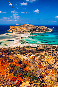 希腊克里特岛的巴洛斯泻湖和格拉姆武萨岛 海鸥飞过 在中心 希腊克里特岛上的 Balos 海滩 Balos 海滩清澈的海水蓝晶旅行背景图片