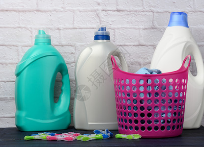粉红色洗衣篮和白砖墙底壁上有液体洗涤剂的塑料瓶高清图片