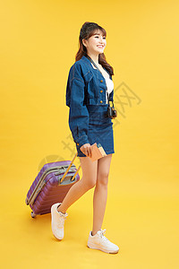 携带彩色背景手提箱的女旅行者航程手提包游客旅行行李女士假期飞机商业女性背景图片