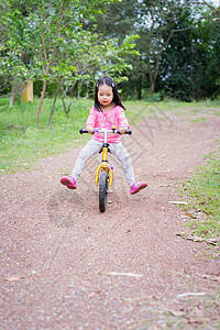 小女孩学会骑平衡的自行车 在公园的斜坡上运动爱好孩子闲暇花园儿童草地女孩乐趣童年背景图片
