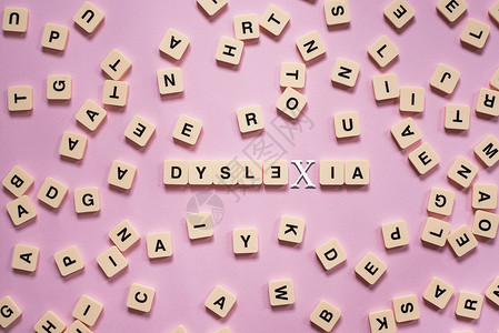 以粉红色背景为中心 DYSLEXIA 单词的字母顺序拼图块智力教育诊断学习帮助学校治疗拼写卫生孩子背景图片