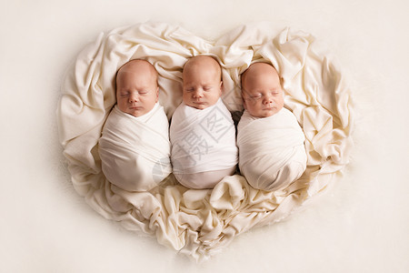 三个睡着的新生儿兄弟 在心脏的背景 (笑声)高清图片
