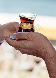 土耳其茶在传统玻璃杯中供应早餐文化勺子款待玻璃乐趣火鸡饮料红色背景图片