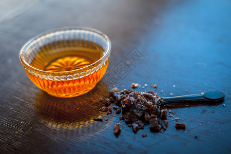 在木质表面的玻璃碗里 紧贴着生蜂蜜 还有黑色勺子中的粉状岩板 帮助人们睡好觉矿物调味品宏观烹饪食物治疗蜂窝金子花蜜水晶背景图片