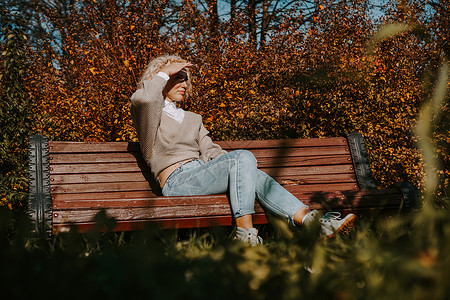 秋天市公园坐在长椅上的女人落叶城市咖啡活动女孩公园成人幸福森林橙子背景图片