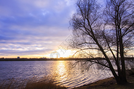 曼托瓦日落在拉脱维亚里加的道格瓦河上 奥克托伯的城市风景海岸旅行风景海岸线天空阳光公园蓝色树木森林背景