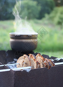 木炭烤面包面包和肉放在烤箱上 旧锅子加香草茶放在烤箱上炙烤母亲幸福篮子童年桌子树叶后院木炭果汁背景