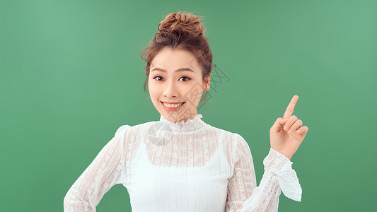 女性促销者手握手 展示绿色背景的广告宣传对象女孩喜悦微笑女士乐趣情感背景图片