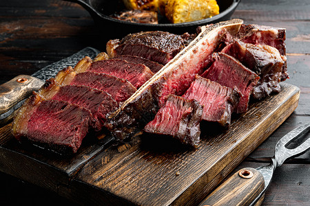 新鲜烤肉 牛肉牛排中稀有的 t骨或门房切割 木制餐板上 旧黑木制桌底背景图片