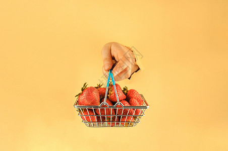 装着草莓篮子女孩手里拿着一个购物篮 里面装着成熟的红草莓 女人的手在撕破的纸上 网上购物的概念顾客购物车营销农业浆果食物饮食水果市场店铺背景