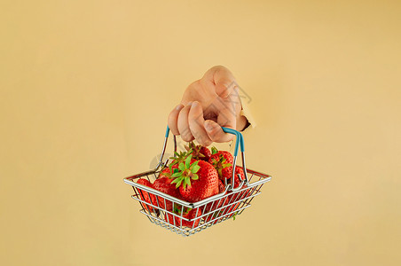 装着草莓篮子女孩手里拿着一个购物篮 里面装着成熟的红草莓 女人的手在撕破的纸上 网上购物的概念浆果购物车食物顾客商业篮子美食市场销售农业背景