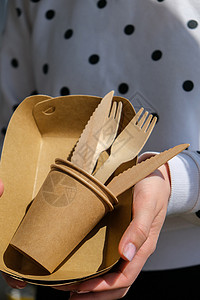 叉子o型女性手握着木质叉子和带有板块的纸杯 生态友好型可支配餐具 用于快餐 餐馆 外卖 野餐包装家庭生活方式女士餐具工艺用具回收纸板杯子背景