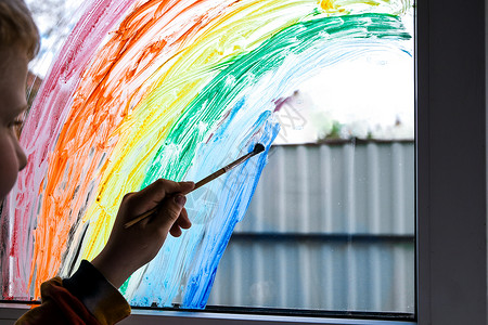 坐在窗户上小男孩在窗户上画彩虹 隔绝时坐在家里 看着窗外的风景 笑声手指艺术家艺术童年保健男生幼儿园学校服务家庭背景