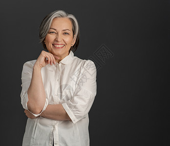 白头发的女商务人士在镜头上笑得开心 美丽的女人穿着花纹衬衫 穿灰色背景 右侧有文字空间背景图片