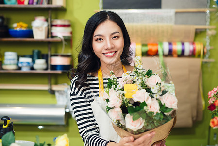美丽的亚裔女性花女 拿着一束花朵女士温室快乐花束商业店铺零售销售微笑花艺背景图片