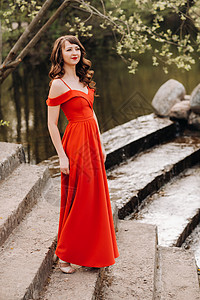 穿着一条长红裙子 从湖边的楼梯上走下来 她从湖边下楼来背景图片