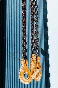 高楼玻璃附近的移动起重机的钩子 吊在吊起架上的链上挂有大量钩子绳索滑轮工具帮助天空商业机械仓库技术重量背景图片