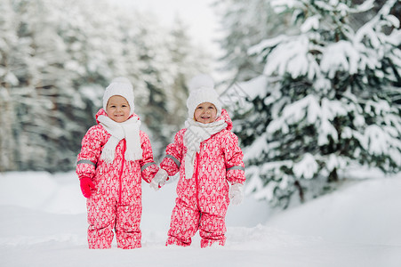 两个穿红西装的小双胞女 站在寒雪的冬季森林里公园婴儿双胞胎新年西装白帽子家庭姐妹孩子们朋友们背景图片