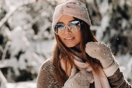 雪堆里小雪人一个穿着毛衣和眼镜的女孩 冬天在一个雪覆盖的森林里女性头发成人新年季节手套快乐微笑女士雪堆背景