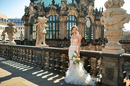 龙年大吉花艺雕塑在德国萨克森州德累斯顿著名的宫举行婚礼散步时穿着白色礼服和花束的新娘背景