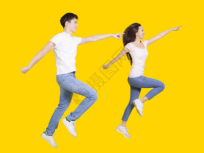 跳跃男人年轻夫妇在复制空间上跳跃和指手画脚 在黄色背景上孤立无援背景