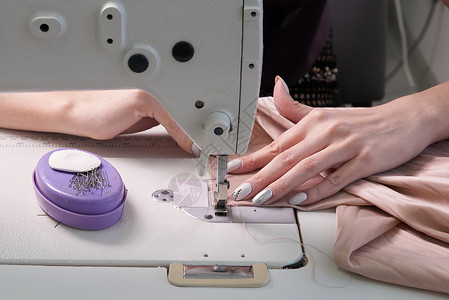 在现代美食店裁缝室使用缝纫机的裁缝匠机器女性衣服接缝作坊剪裁工作工具爱好裙子背景图片