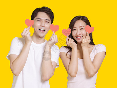 台湾红心番显示红心形状的年轻夫妇 孤立于黄色背景背景