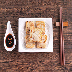 美味的萝卜蛋糕 中国传统红菜蛋糕 在餐厅里配有酱油做新年菜 特写 复制空间 顶层视野 平铺桌子早餐盘子小吃筷子文化木头食物美食大背景图片