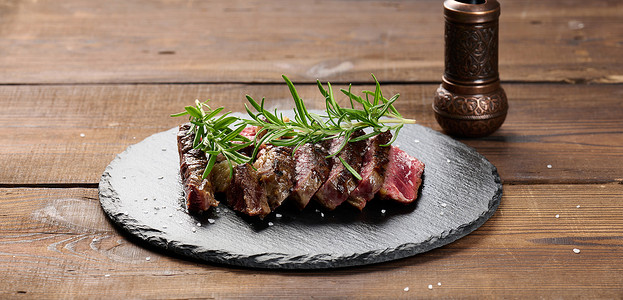 胡椒碎在黑板上切成碎片的炸牛肉肉 鲜有熟食度 美味牛排迷迭香炙烤肋眼黑色木板牛扒胡椒食物横幅草本植物背景