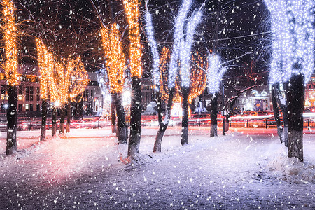 冬季夜间公园下雪 有圣诞节装饰品 灯光 铺满雪和树木的行人道灯笼小路公共公园调子冻结城市圣诞人行道降雪彩灯背景图片