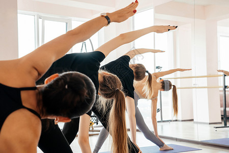 一群穿着运动服的迷人运动女孩在健身馆锻炼 在健身房的垫子上做瑜伽姿势锻炼的年轻健康女性男人讲师地面平衡俱乐部团体冥想娱乐训练班级背景图片