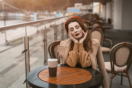 晚上在城市街道上拿着咖啡杯的巴黎女人 迷人的女人坐在春天的露天咖啡馆里享用她的咖啡 红色贝雷帽的法国妇女有都市背景成人时尚闲暇女背景图片