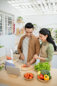 根据平板电脑上的食谱 一起烹饪的一对漂亮的年轻夫妇的肖像电子男人夫妻药片工具厨房炊具网站互联网女士背景图片