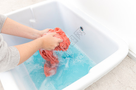 蓝色浴缸女性用手在水槽中洗彩色衣服泡沫服务棉布肥皂洗涤剂清洁工工作衬衫房间浴缸背景