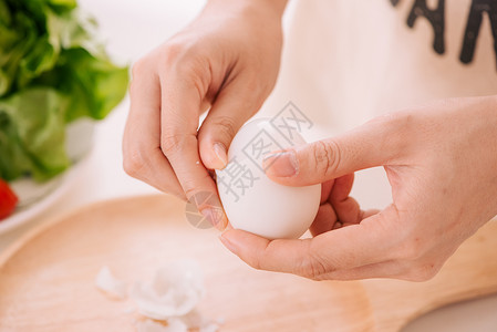 女性的手正在剥鸡蛋 女人在家准备早餐 在深色桌子上的木器中煮鸡蛋 复古色调蛋壳成人营养黄色女孩食物白色女士烹饪背景