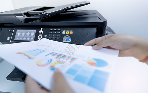 上班族在多功能激光打印机上打印纸张 办公室内的复印 打印 扫描和传真机 文件和文书工作 打印技术 模糊的手拿着打印的纸 扫描设备背景图片