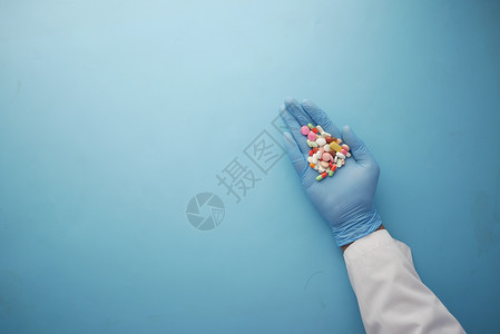 手掌上持有医用药片的医生药品医疗手套蓝色诊所乳胶棕榈背景图片