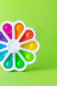 用手指反压力的玩具按压 将它弹出在绿色背景上 多彩的硅酮爆状玩具 泡泡小费 简单小便背景图片