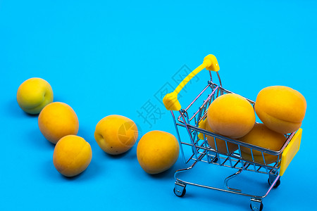 蓝色背景的有杏子的购物篮 购物车零售杂货店甜点食物贸易水果销售商品消费者店铺背景图片