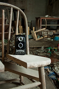 旧胶片摄影机坐在一个破碎椅子上的乱糟糟的车间里背景图片