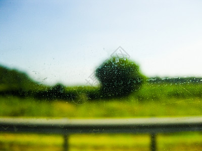 通过窗口场景绿色灌木 草草和通过肮脏窗口的公路铁路背景