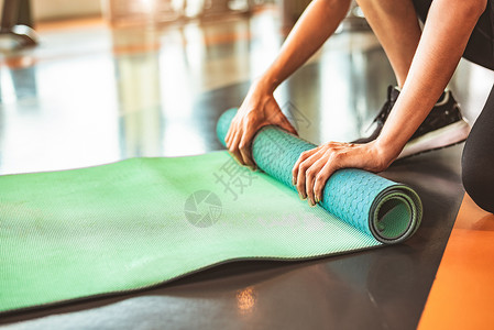 地毯垫在运动健身健身房训练中心背景下特写运动型女性折叠瑜伽床垫 瑜伽课后保持运动垫滚动 锻炼和运动训练概念 手放在地毯上运动装冷却活动背景