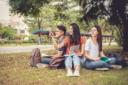 一群亚洲大学生在户外草地上阅读书籍和辅导特殊课程 幸福与教育学习理念 回到学校的概念 青少年和人的主题男人团体朋友们药片女孩女性背景图片