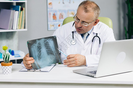 高级男医生看着电脑屏幕在网络聊天咨询客户在线上通过网络摄像头进行交流 年长的医生与在笔记本电脑上进行视频通话的病人交谈背景图片