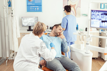 接受口腔科咨询期间检查病人牙痛的高级妇女肿瘤病理学专家考试调查问卷讨论椅子牙齿护士口腔科办公室访问治疗背景图片