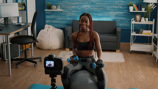 黑人女教练在健身球上做晨瑜伽练习 坐在健身雪球上互联网运动哑铃身体技术姿势记录培训师有氧运动运动员背景图片