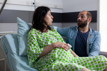缩唇呼吸怀孕的年轻夫妇 在医院病房床上睡觉父亲男人孩子保健母亲椅子丈夫监控呼吸家庭背景