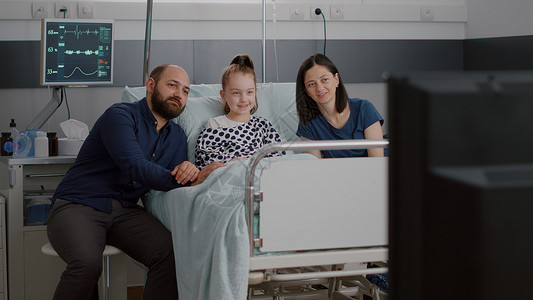 住院生病小病人与家人躺在床上 在电视上看娱乐电影的家属一起看戏房间父亲微笑病房治疗孩子考试手术临床卡通片背景